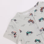 Close up shot of a children's onesie with vehicle patterns on a light gray background