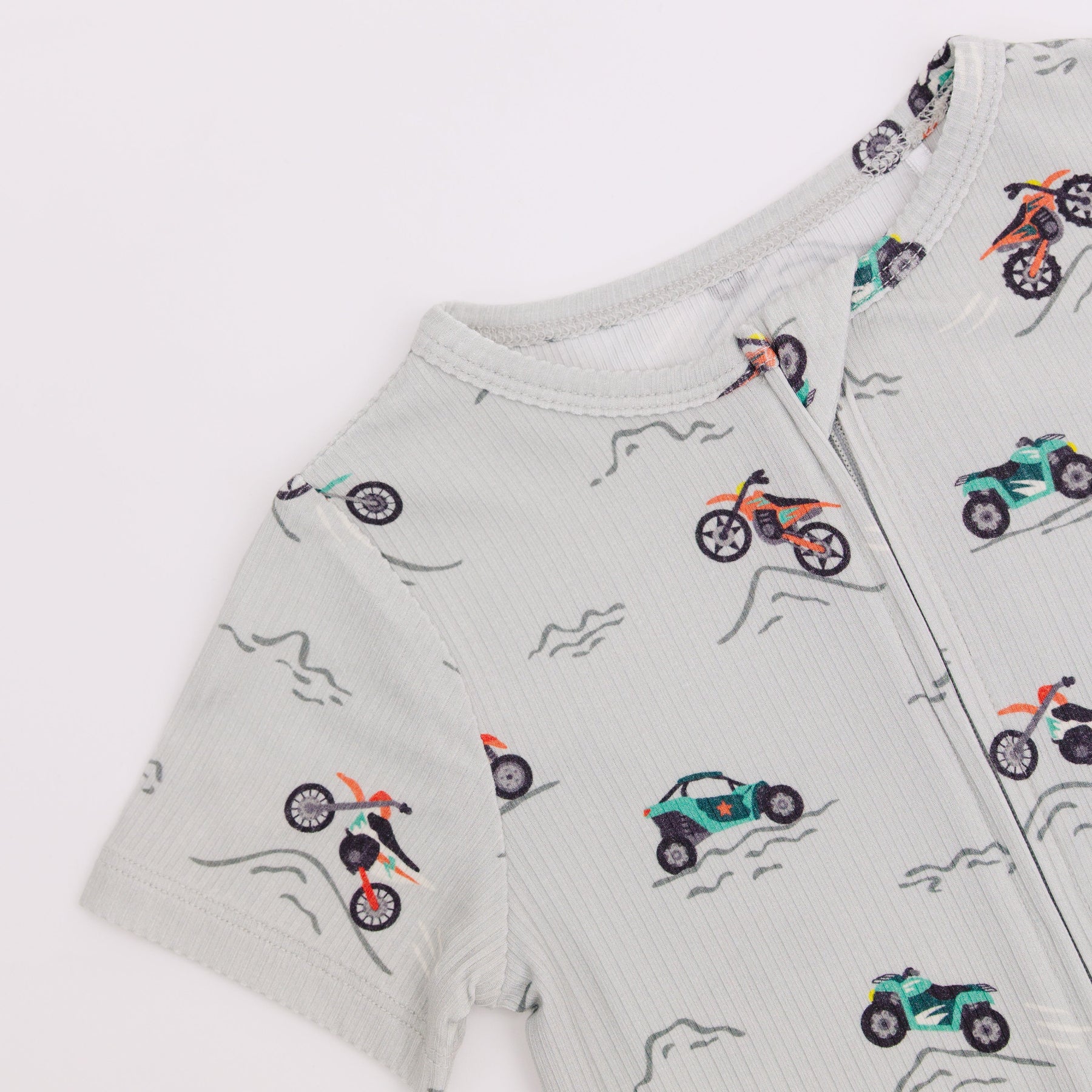 Close up shot of a children's onesie with vehicle patterns on a light gray background