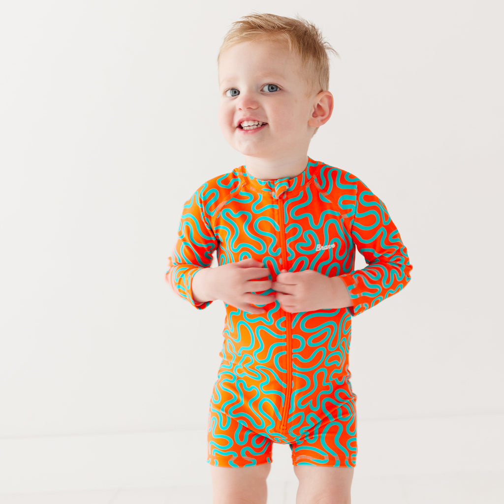 Child wearing a colorful swimsuit with a squiggly pattern on a white background