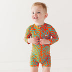 Child wearing a colorful swimsuit with a squiggly pattern on a white background
