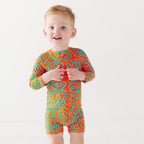 Child wearing a colorful swimsuit with a squiggly pattern on a white background