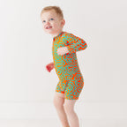 Child wearing a colorful swimsuit with a squiggly pattern on a white background