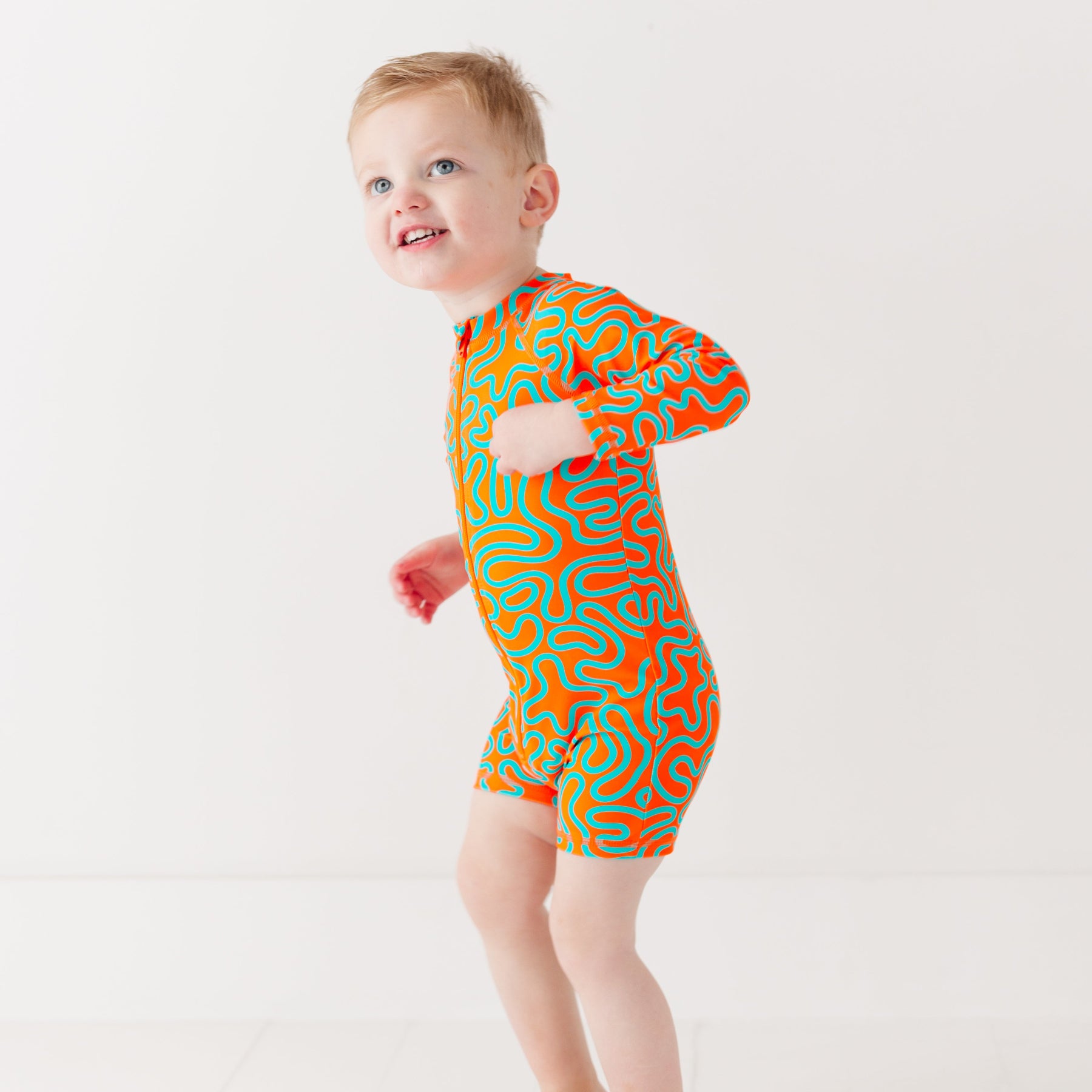 Child wearing a colorful swimsuit with a squiggly pattern on a white background