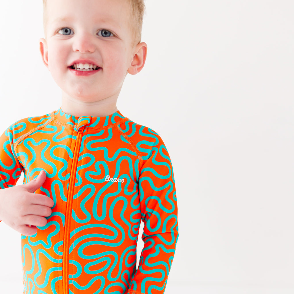 Child wearing a colorful swimsuit with a squiggly pattern on a white background