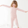 Child wearing a pink striped long sleeve pajama set on a white background