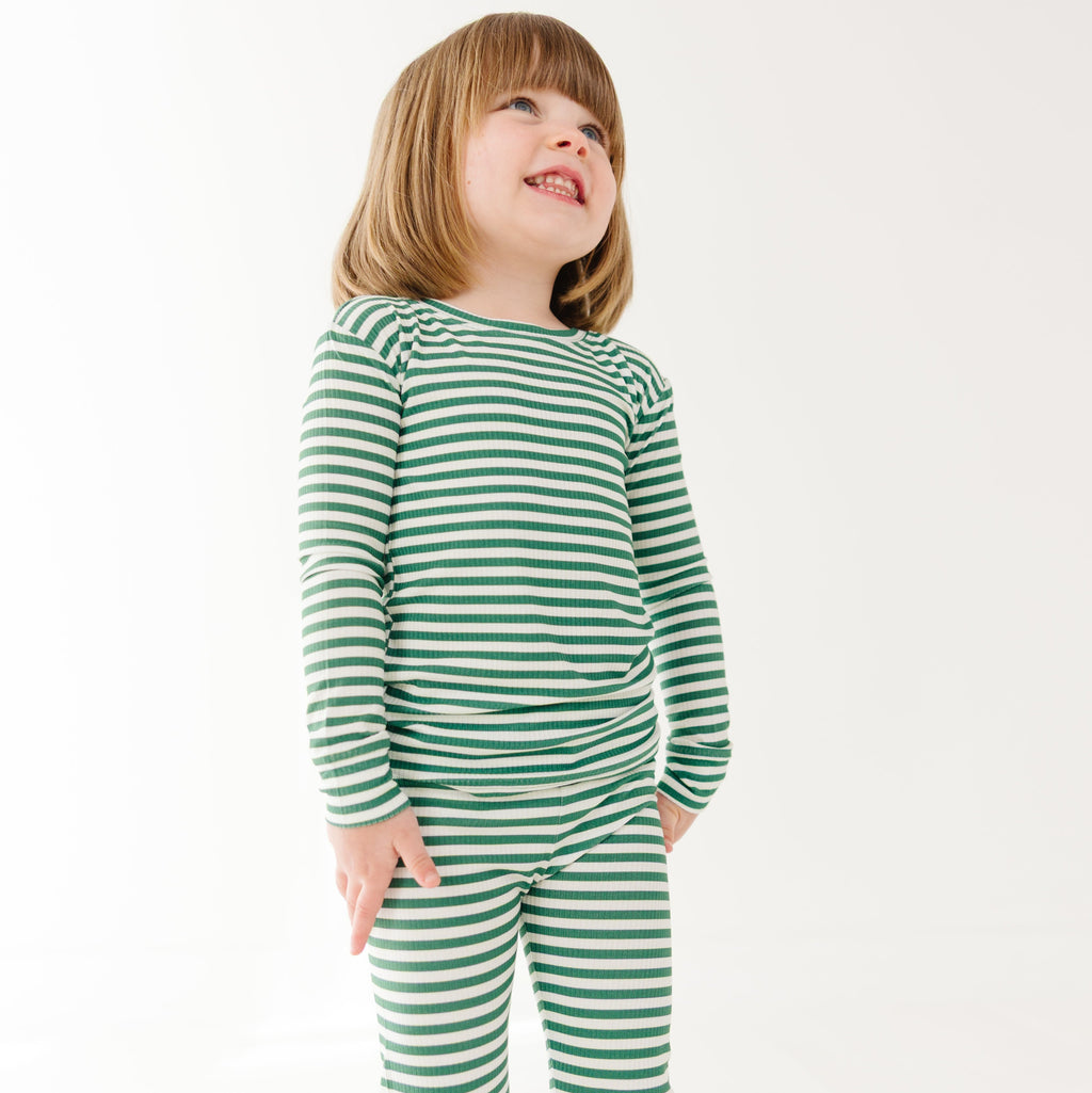 Child wearing green and white striped pajamas on a white background