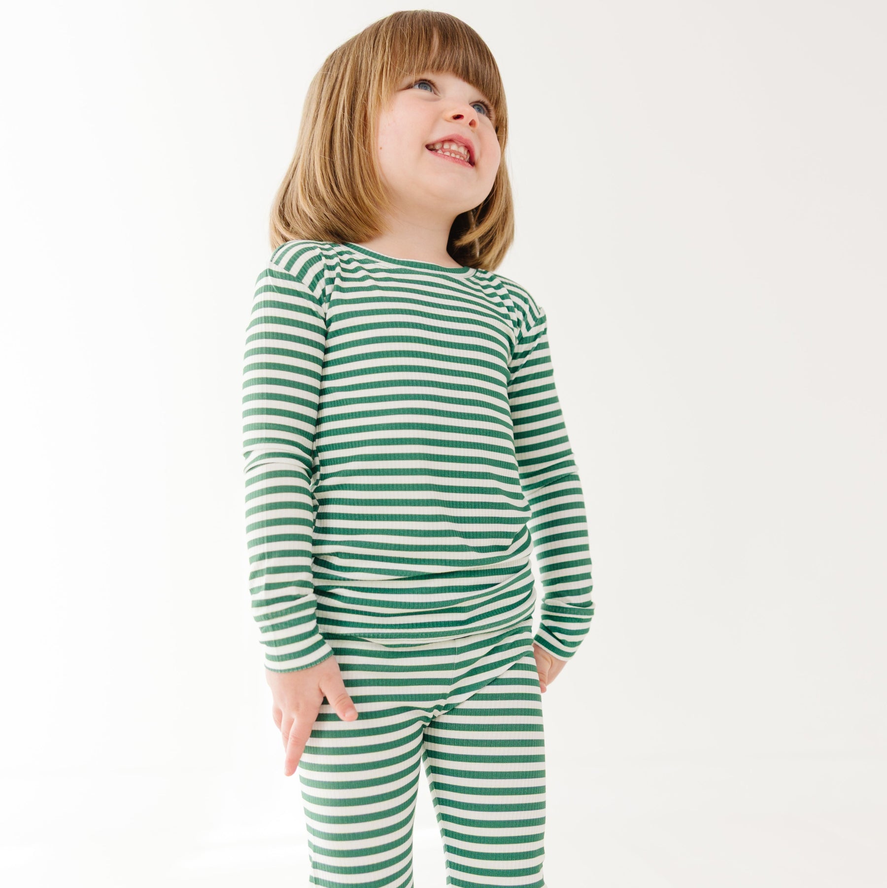Child wearing green and white striped pajamas on a white background