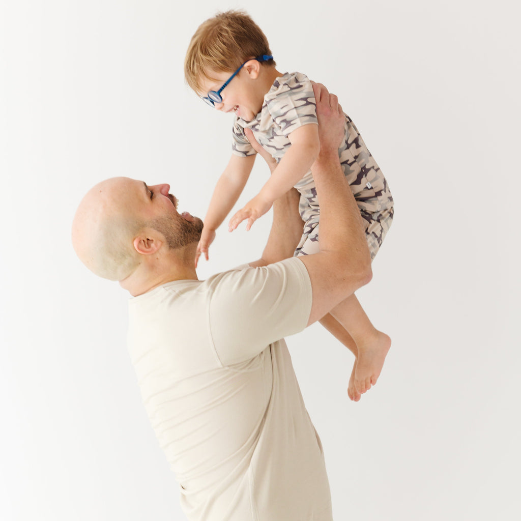 Man lifting a child in the air against a white background