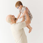 Man lifting a child in the air against a white background