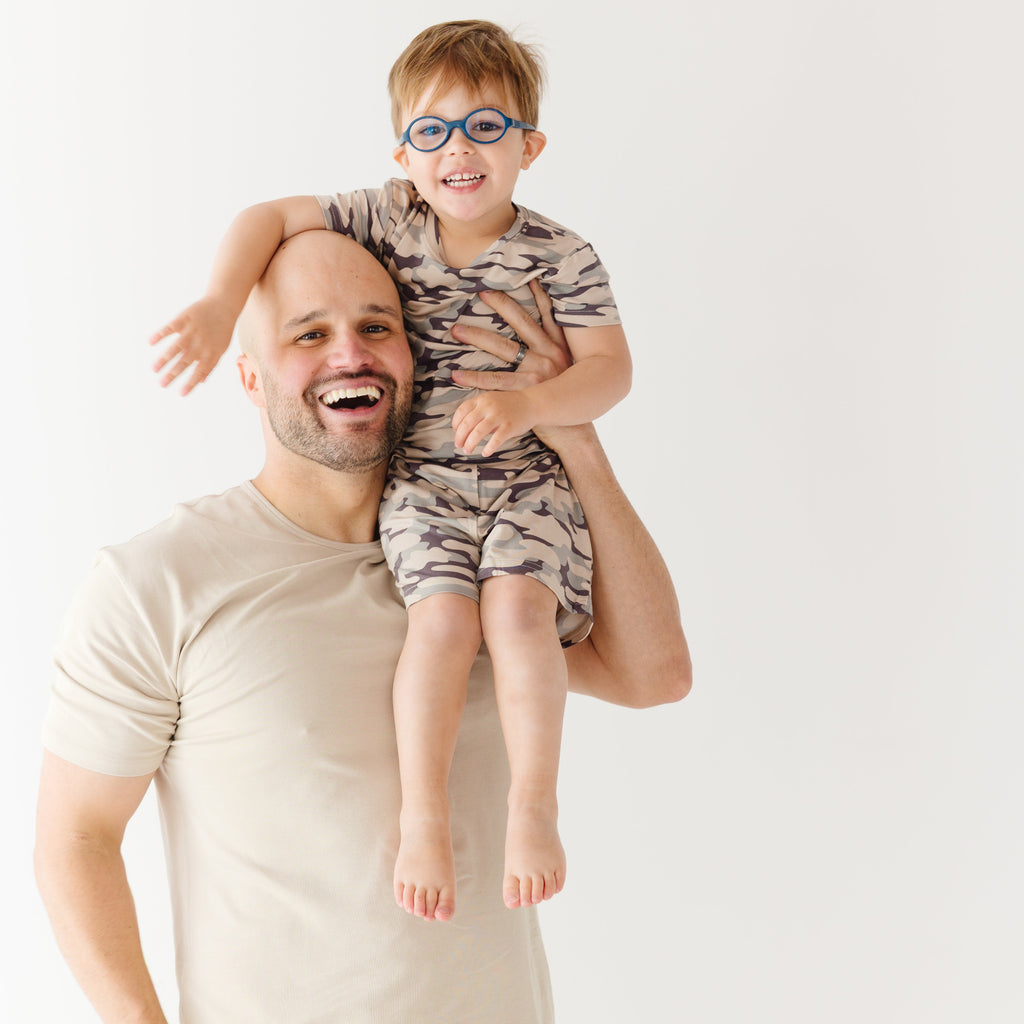 Man holding a child on his shoulders against a white background