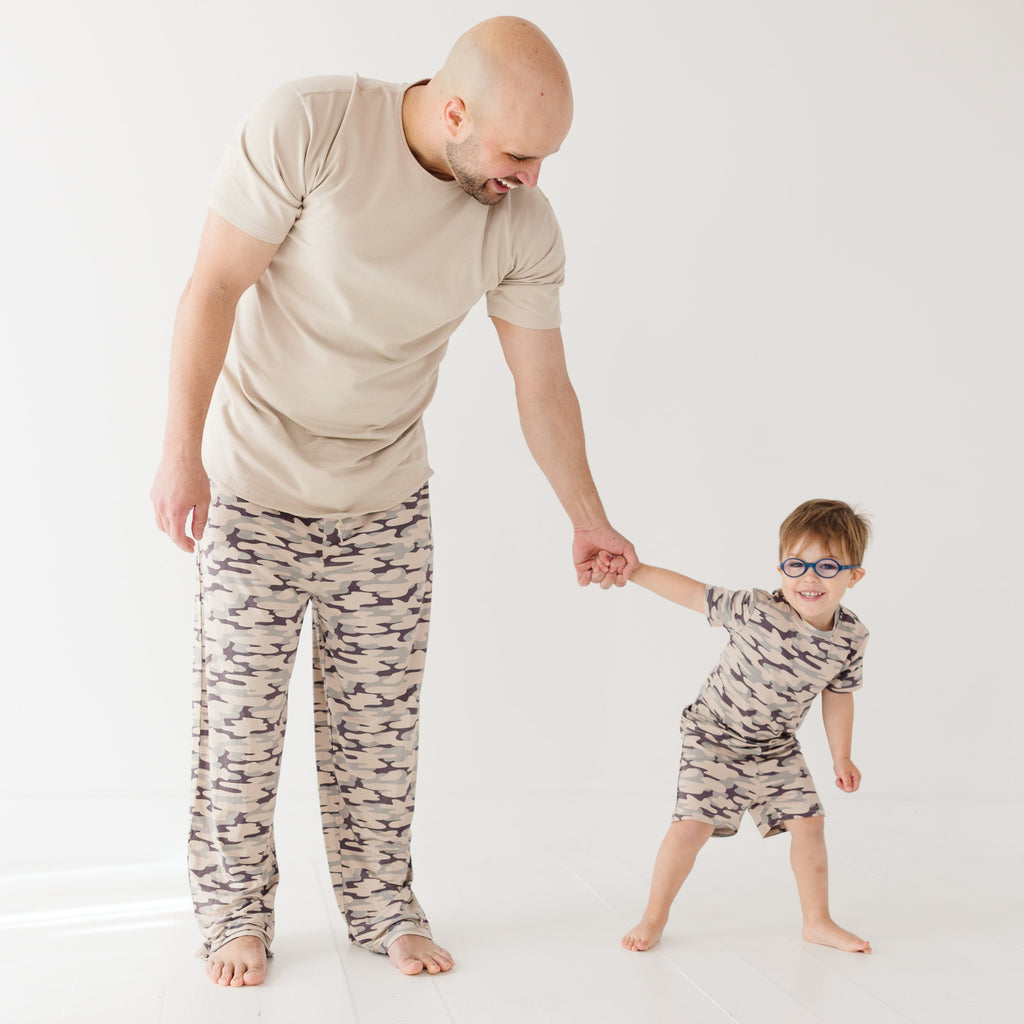 Man and child wearing matching camouflage pajamas on a white background