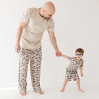 Man and child wearing matching camouflage pajamas on a white background