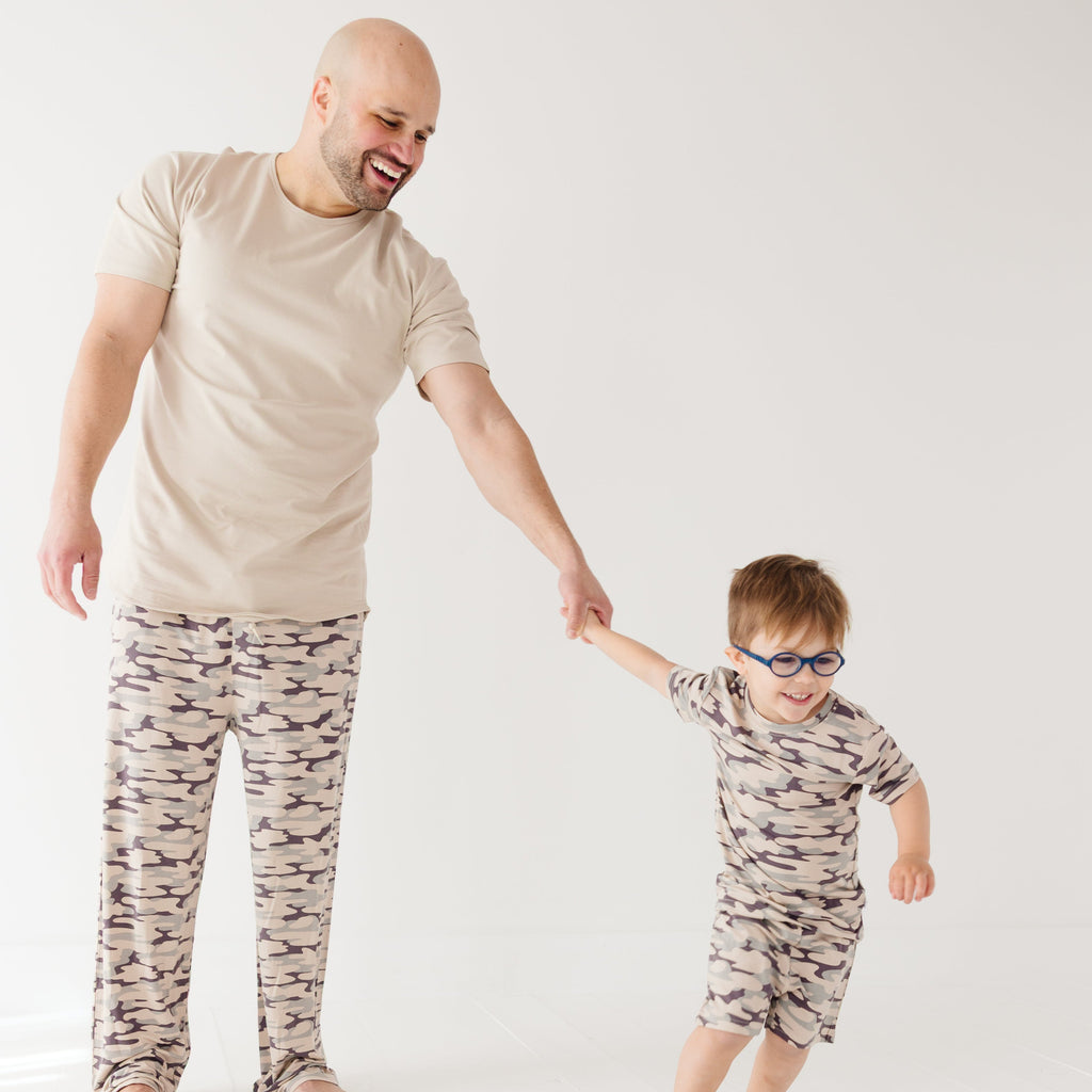 Man and child wearing matching camouflage outfits on a white background