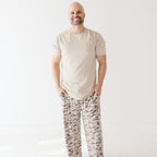 Man wearing a beige t-shirt and camouflage-patterned pants on a white background