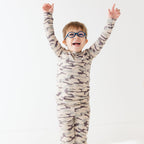 Child wearing a camouflage long sleeve pajama set on a white background