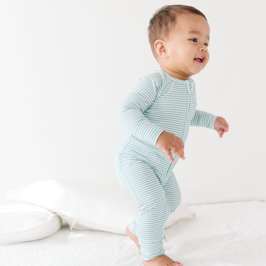 Baby wearing a light blue and white striped onesie on a plain background