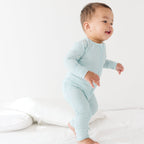 Baby wearing a light blue and white striped onesie on a plain background