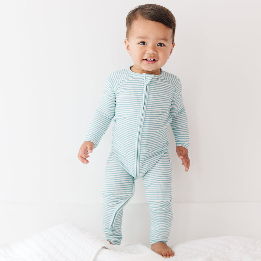 Baby wearing a light blue and white striped onesie on a plain background