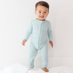 Baby wearing a light blue and white striped onesie on a plain background