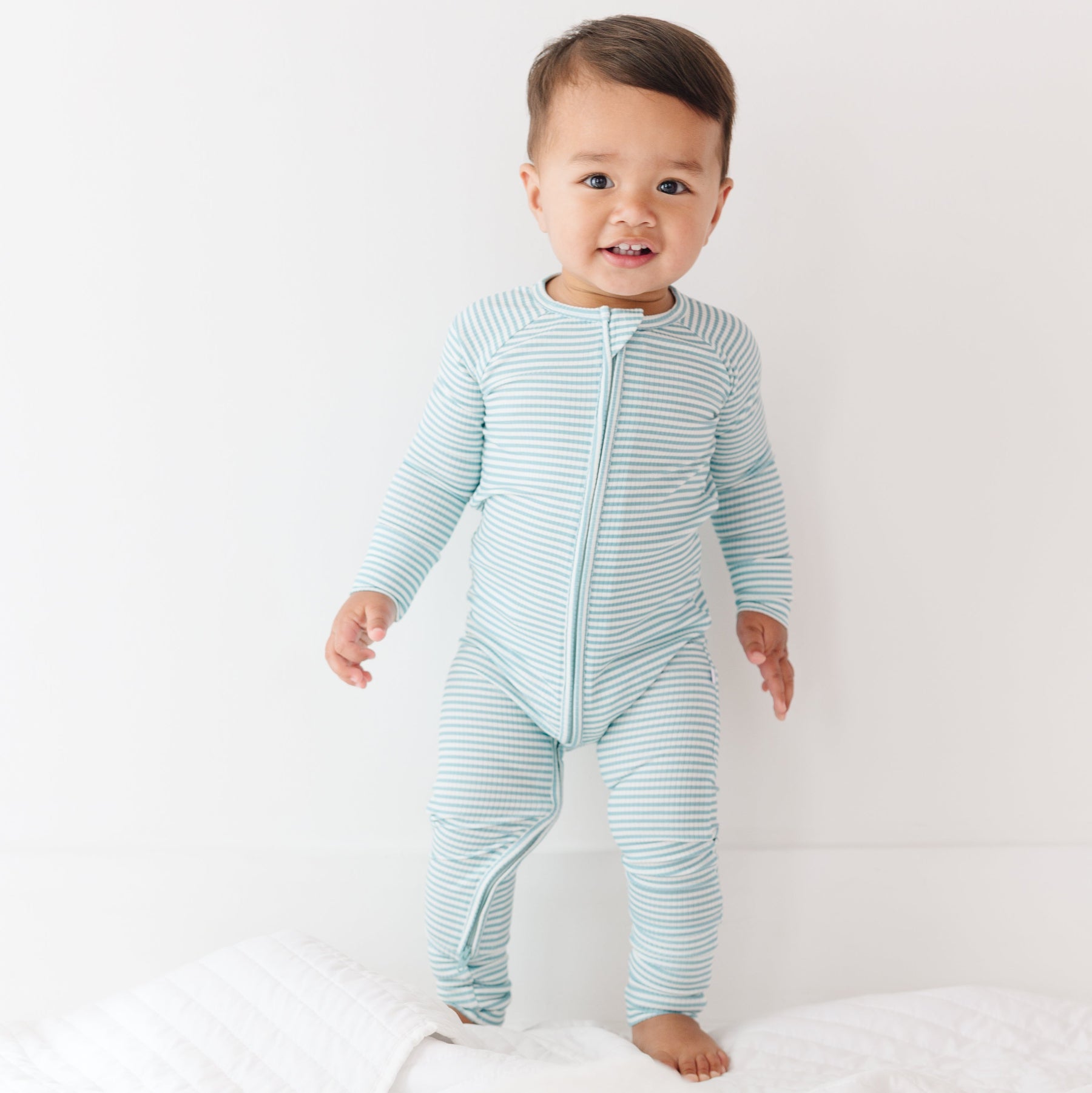 Baby wearing a light blue and white striped onesie on a plain background