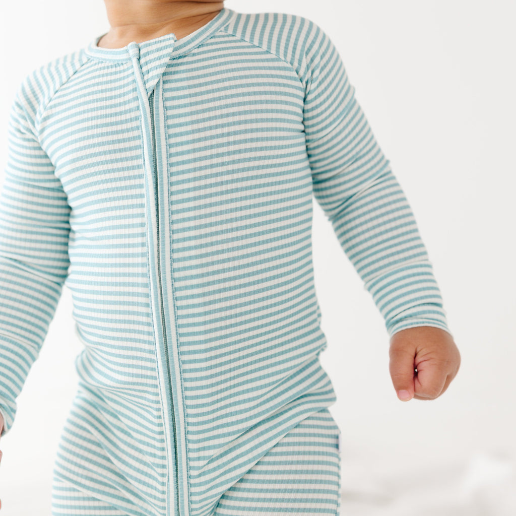 Baby wearing a light blue and white striped onesie on a plain background
