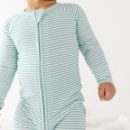 Baby wearing a light blue and white striped onesie on a plain background