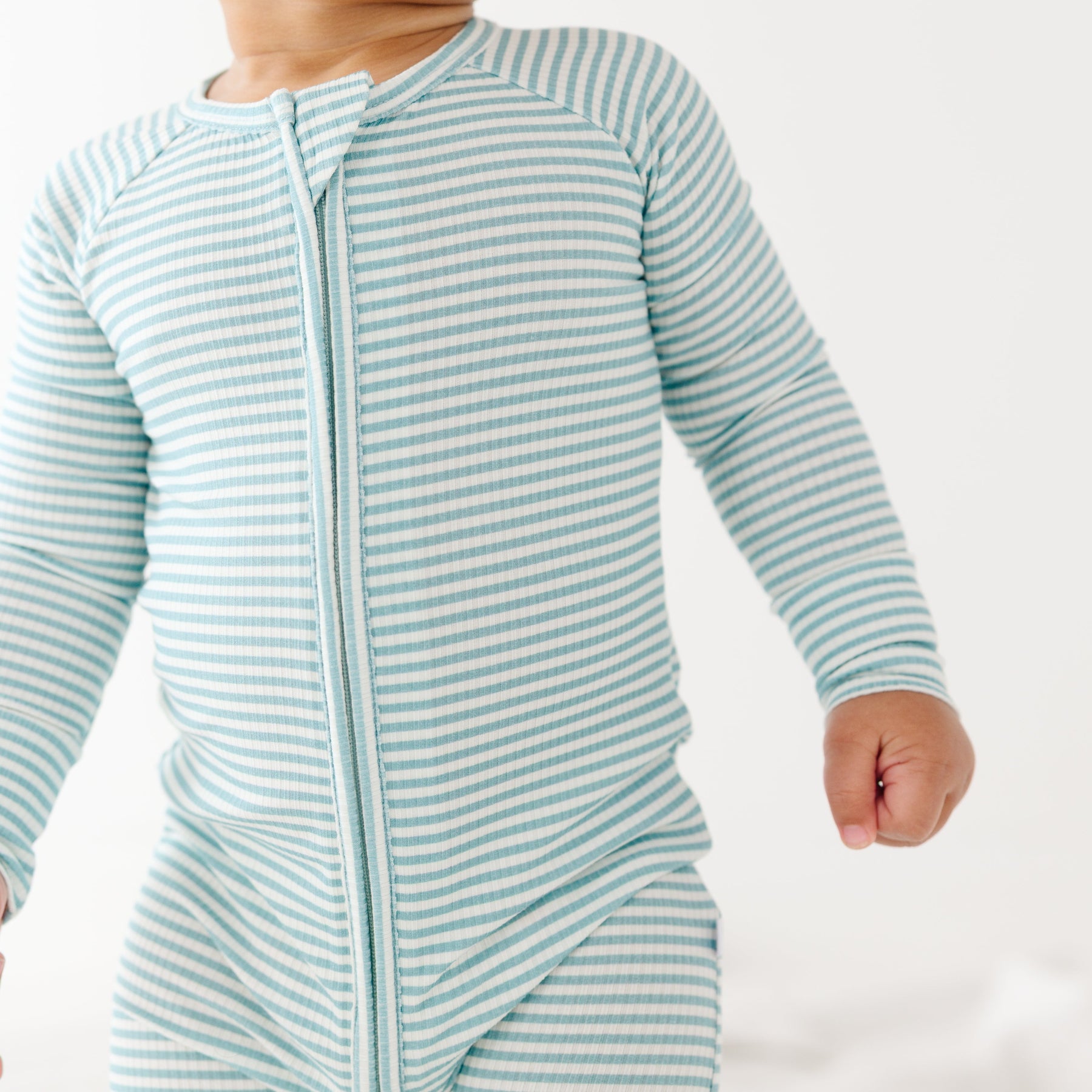 Baby wearing a light blue and white striped onesie on a plain background