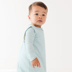 Baby wearing a light blue striped onesie and sleep sack on a white background