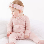 Baby wearing a pink striped outfit and headband on a white background