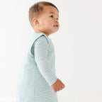 Baby wearing a light blue striped onesie and sleep sack on a white background