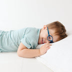 Child lying on a bed wearing a blue and white striped pajama set