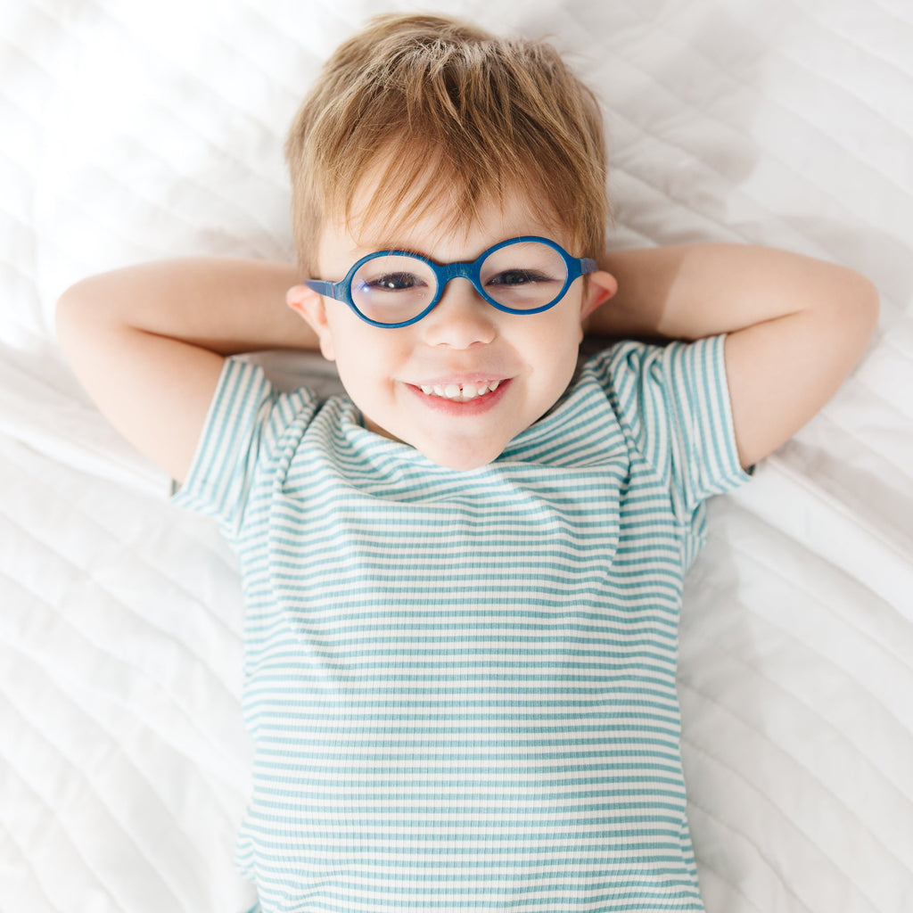 Child lying on a bed wearing a blue and white striped pajama set