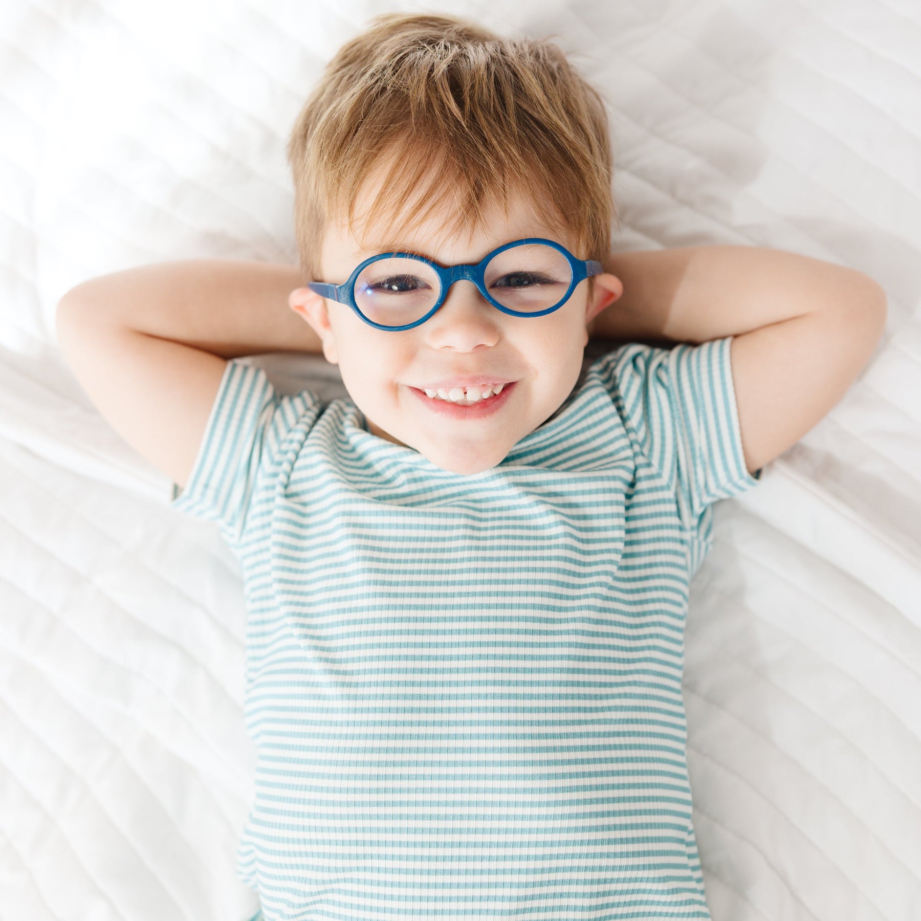 Child lying on a bed wearing a blue and white striped pajama set