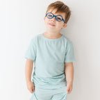 Child wearing a light blue striped shirt and shorts set on a white background