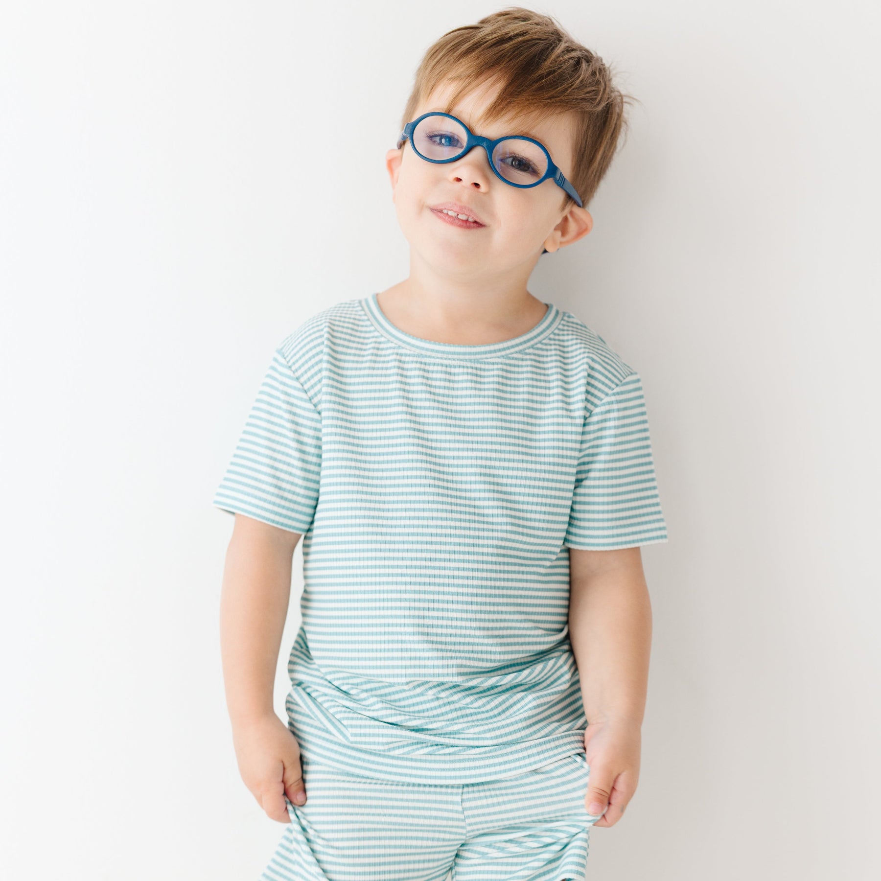 Child wearing a light blue striped shirt and shorts set on a white background