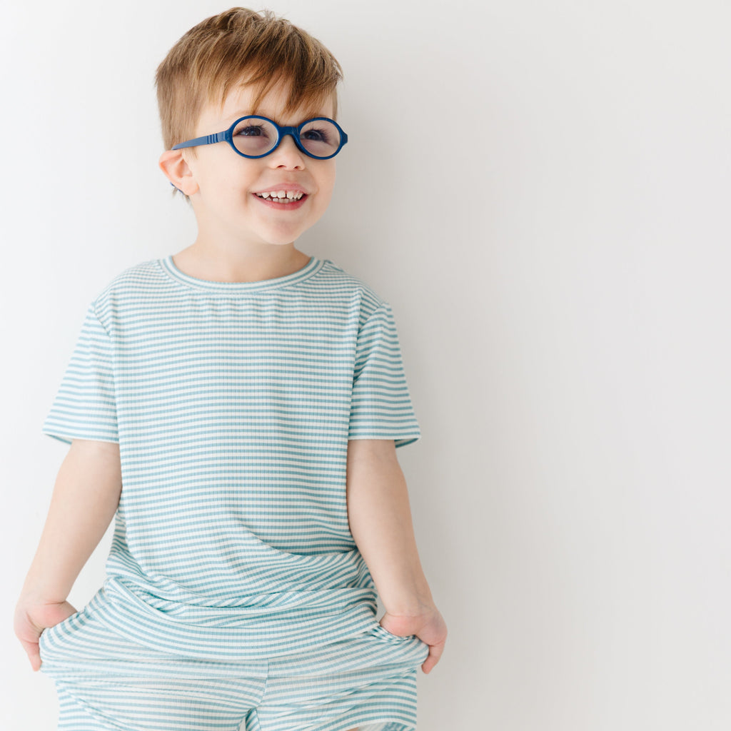 Child wearing a light blue striped shirt and shorts set on a white background