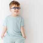 Child wearing a light blue striped shirt and shorts set on a white background