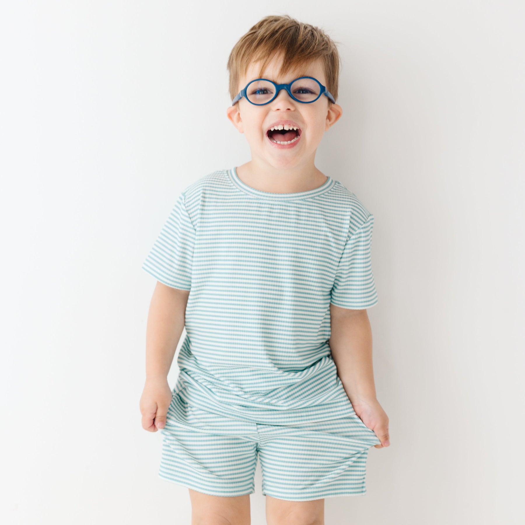 Child wearing a light blue striped shirt and shorts set on a white background