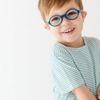 Close up of a child wearing a light blue striped shirt and shorts set on a white background