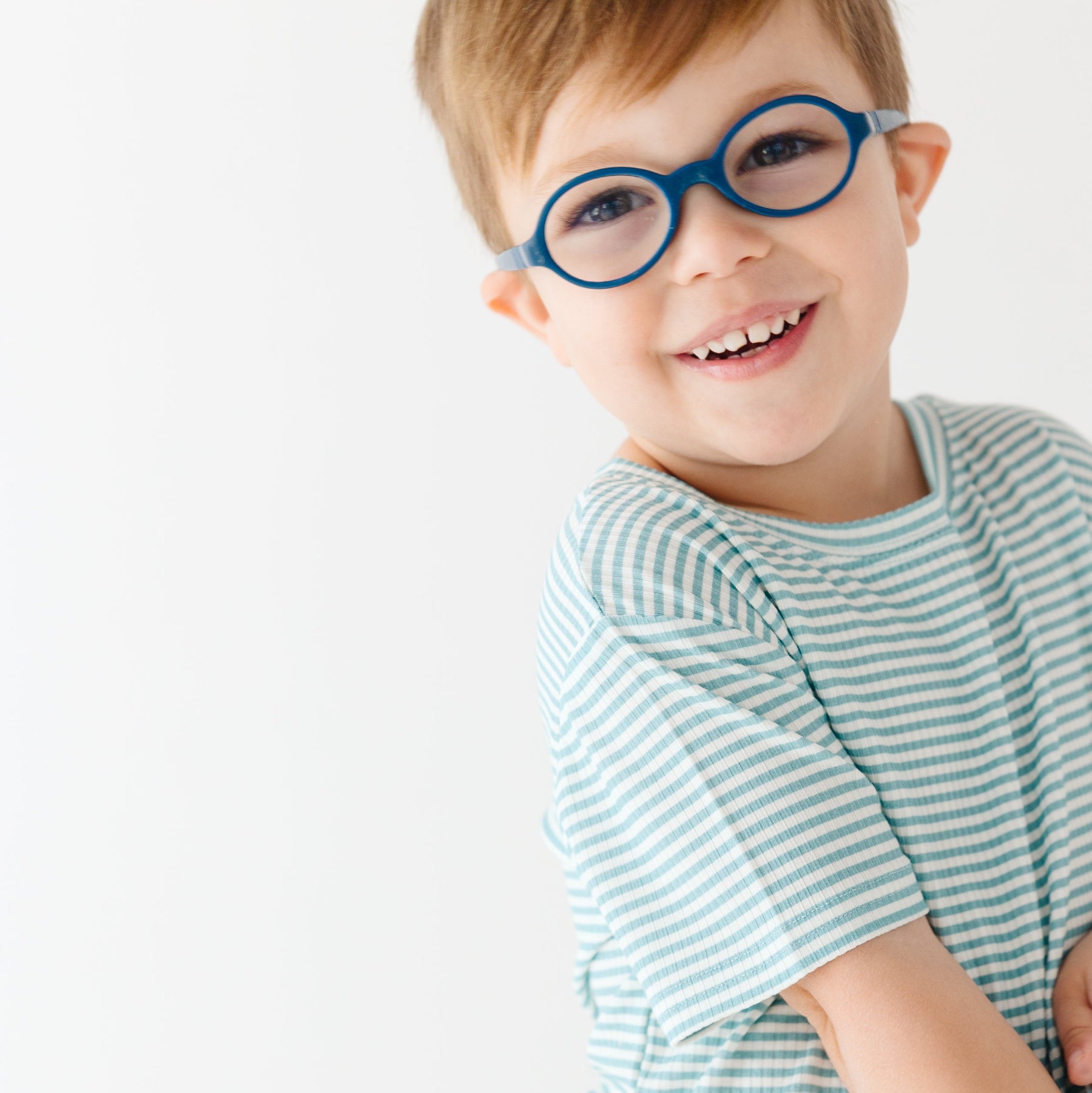 Close up of a child wearing a light blue striped shirt and shorts set on a white background