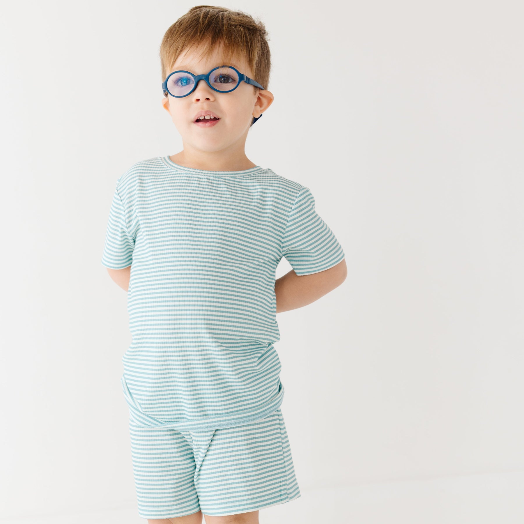 Child wearing a light blue striped shirt and shorts set on a white background