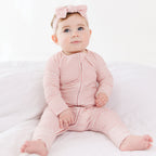 Baby wearing a pink striped outfit and headband on a white background