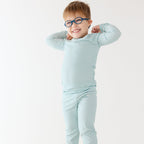 Child wearing a light blue striped pajama set on a white background