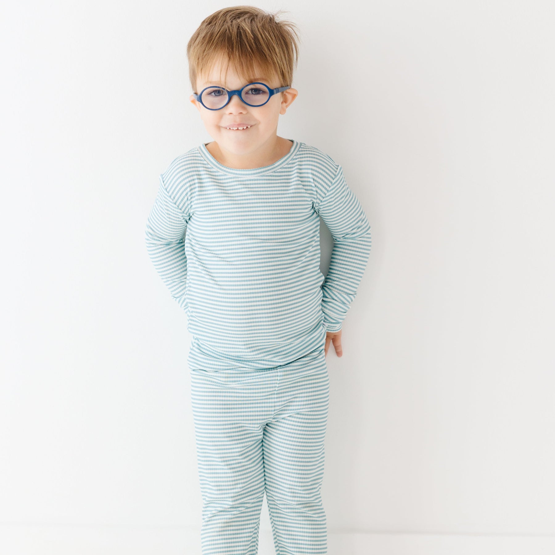 Child wearing a light blue striped pajama set on a white background