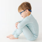 Child wearing a light blue striped pajama set on a white background