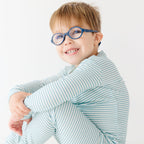 Child wearing a light blue striped pajama set on a white background