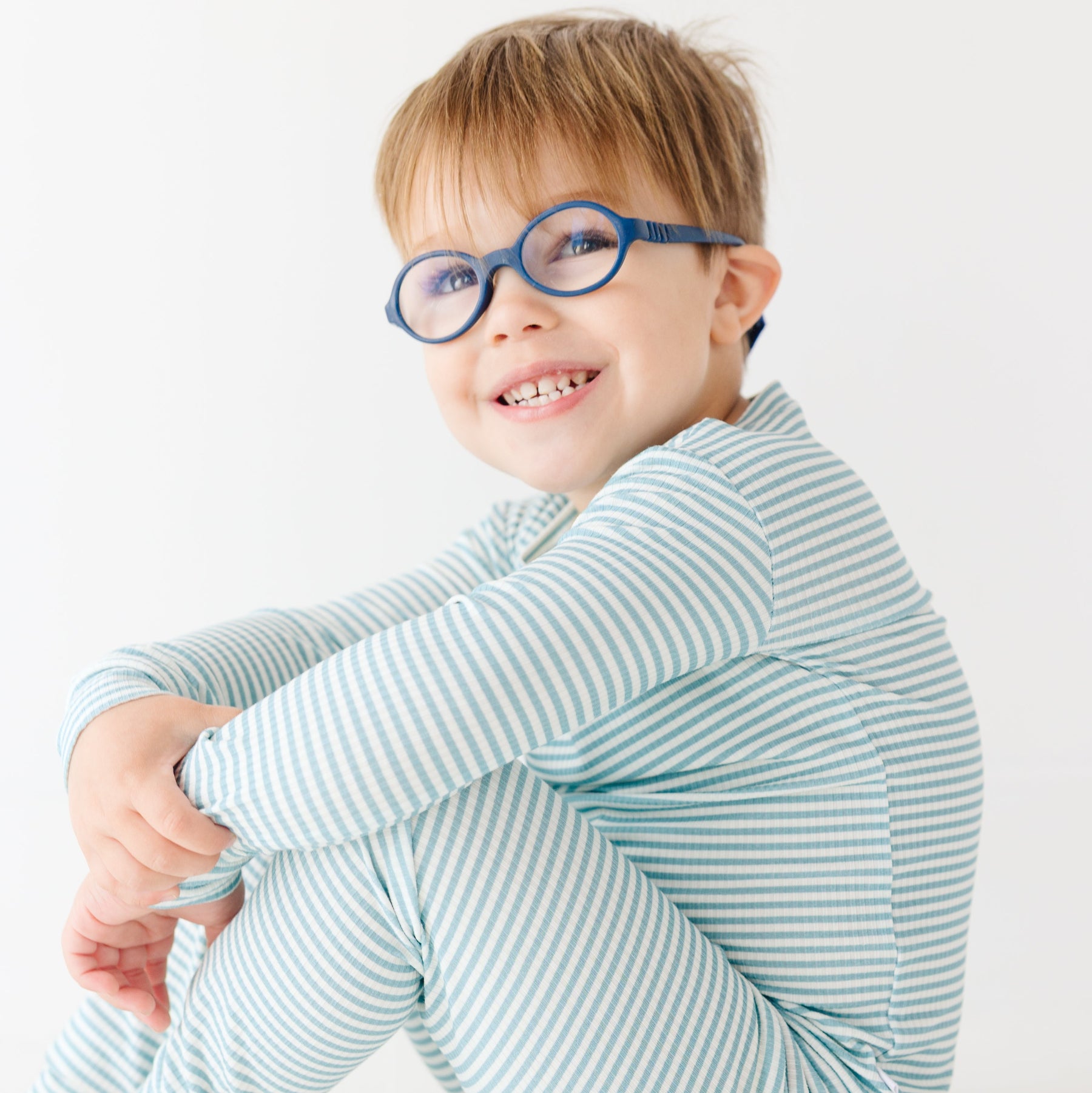 Child wearing a light blue striped pajama set on a white background