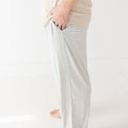 Man wearing a beige t-shirt and light gray pants on a white background