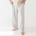 Person wearing light gray pajama pants on a white background