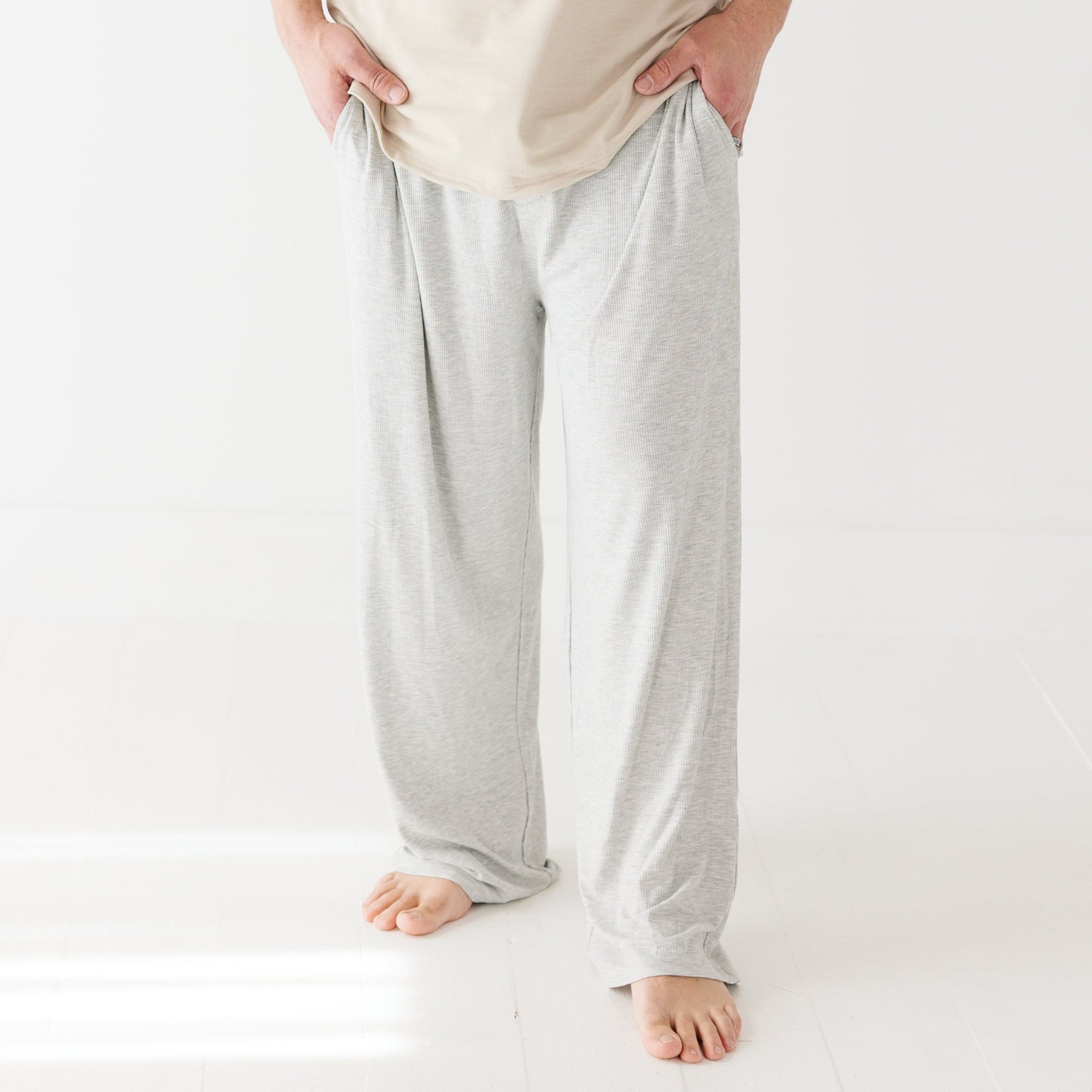 Person wearing light gray pajama pants on a white background